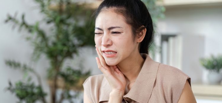 A woman holding her jaw in pain, reflecting common dental issues