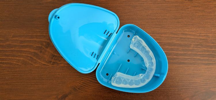 Clear boil-and-bite mouthguard in a blue storage case on a wooden surface