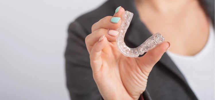Woman showing a clear dental night guard designed for teeth grinding and jaw protection