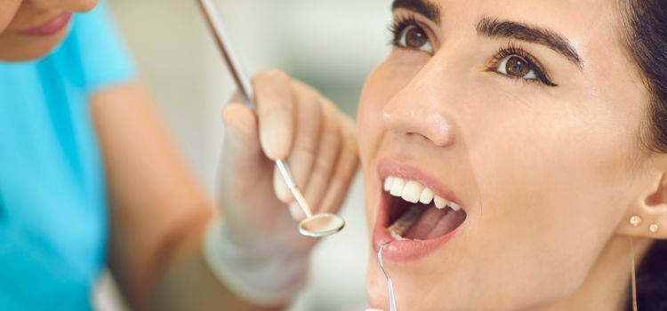 Dental exam for bite problems and bruxism Woman at a dental check-up with a dentist examining her bite using a dental mirror.