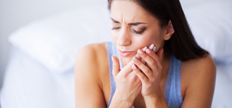 Woman in pain holding her cheek, showing discomfort from a cheek bite