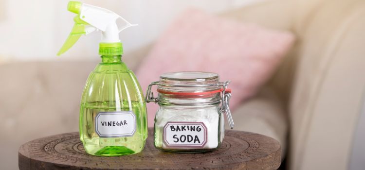 Glass jar labeled baking soda and spray bottle of vinegar used for natural night guard cleaning at home.